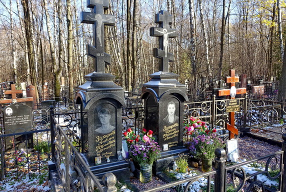 Два похожих гранитных памятника и простой православный крест